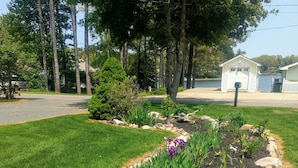 A landscaped garden with a variety of plants and a small white building in the background.