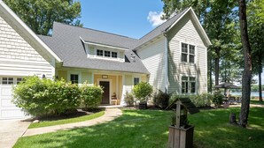A two-story house with a front porch, a small garden, and a wooden birdhouse. - Modern Lakefront Retreat Sleeps 13, a 4-Season Getaway 2 Hours from Chicago (decatur)