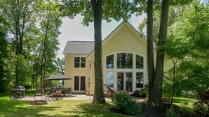 A yellow house with a large porch, surrounded by trees and a well-maintained lawn. - Modern Lakefront Retreat Sleeps 13, a 4-Season Getaway 2 Hours from Chicago (decatur)