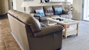 Ein Wohnzimmer mit einem braunen Ledersofa, einem Glastisch und einem Teppich.