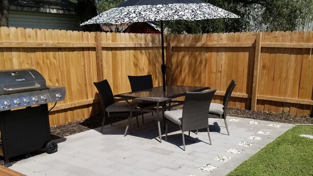 A backyard patio with a grill, dining table, chairs, and an umbrella. - Historically Modern Delano (Wichita)