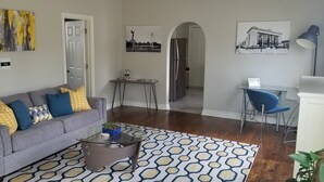 A living room with a grey sofa, patterned rug, and a coffee table. - Historically Modern Delano (Wichita)