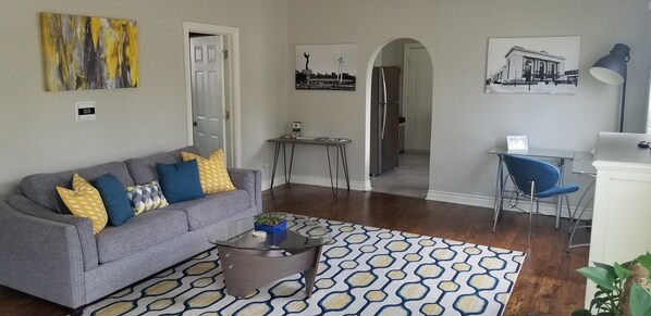 A living room with a grey sofa, patterned rug, and a coffee table. - Historically Modern Delano (Wichita)