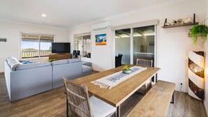 Una sala moderna con una mesa de comedor de madera, un sofá gris y un televisor.