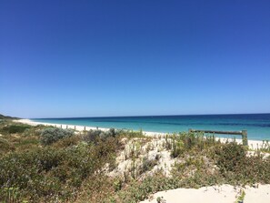 Ein Strand mit Holzzaun und Vegetation im Vordergrund.