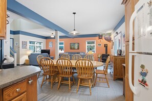 A kitchen with a round dining table, wooden chairs, and a refrigerator with a cartoon sticker.