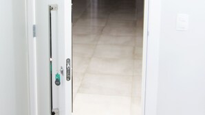 Ein Flur mit einer Tür zu einem Zimmer. Der Flur hat einen gefliesten Boden und eine Leuchte an der Decke.