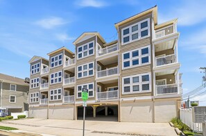 A multi-story residential building with balconies, a garage entrance, and a clear sky.