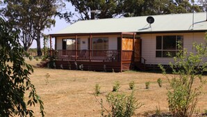 A single-story house with a porch, a satellite dish, and a dry grassy yard.