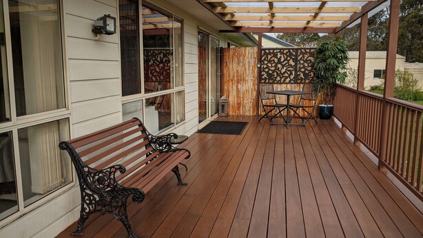 A wooden deck with a pergola, two benches, and a table.