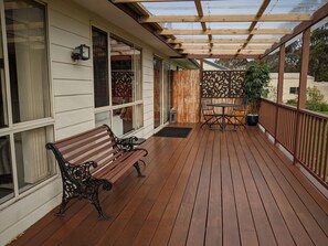 Eine Holzterrasse mit einer Pergola, zwei Bänken und einem Tisch.