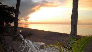 A beach with white lounge chairs and a lamp post, palm trees, and a sunset over the ocean. - Beautiful 4 Bed Thai Style Villa ideal for all the family (Koh Samui)