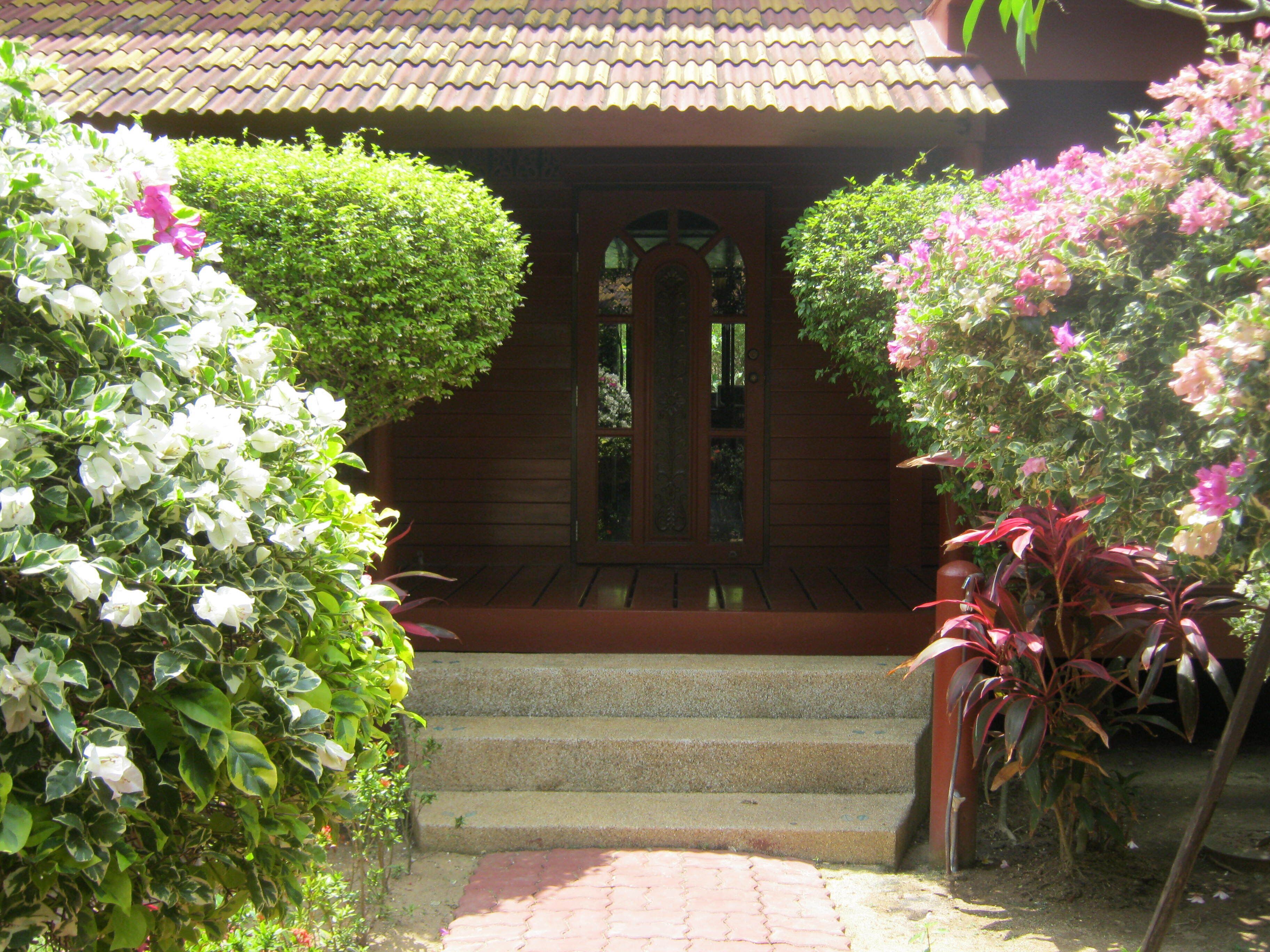 Una casa de madera con techo de tejas, puerta de cristal y un conjunto de escalones de piedra que llevan a la entrada.