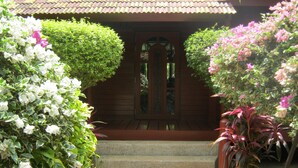 A wooden house with a tiled roof, a glass door, and a set of stone steps leading to the entrance. - Beautiful 4 Bed Thai Style Villa ideal for all the family (Koh Samui)