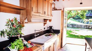 A kitchen with wooden cabinets, a sink, and a countertop with fresh vegetables. - Luxury Villa Tuscany (Bagni di Lucca)