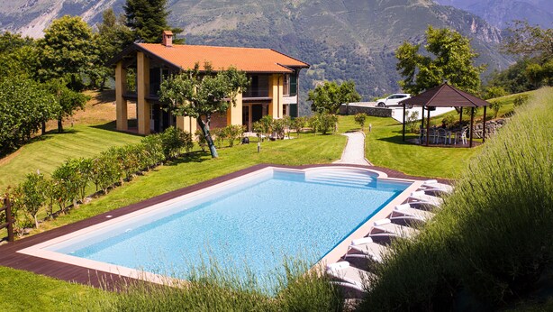A pool with a wooden deck, a gazebo, and a mountain backdrop. - Luxury Villa Tuscany (Bagni di Lucca)