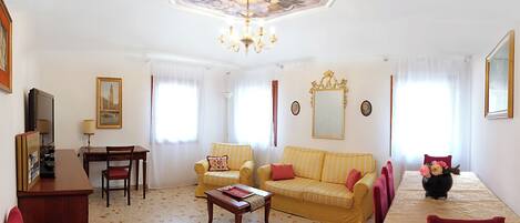 A spacious living room with a chandelier, a sofa set, a dining table, and a coffee table.