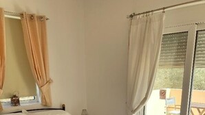 A bedroom with a bed, a bedside table, a lamp, and a window with curtains. - Nineteen 5* reviews. Book 2025 now (Lardos)
