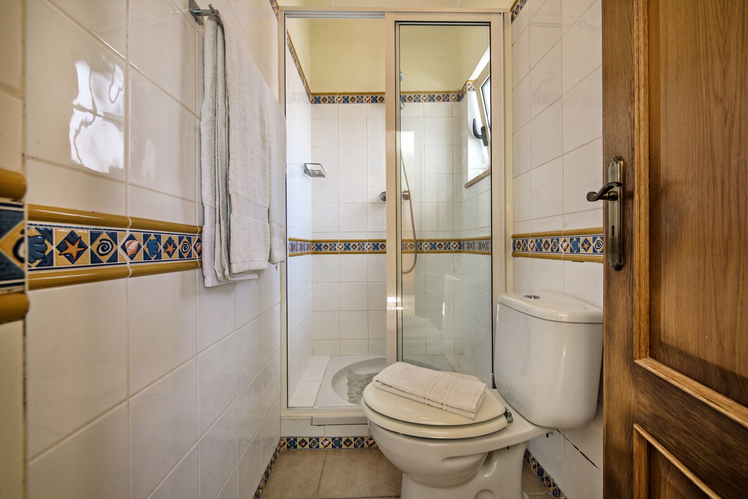 A small bathroom with a toilet, shower, and glass door.