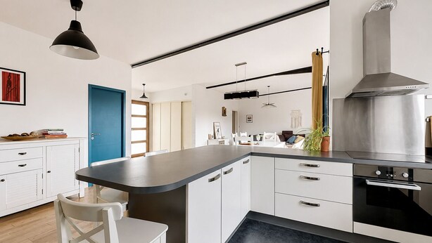 Una cocina moderna con armarios blancos, encimera negra y electrodomésticos de acero inoxidable.