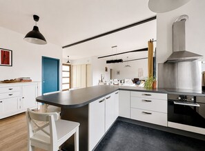 A modern kitchen with white cabinetry, a black countertop, and stainless steel appliances.