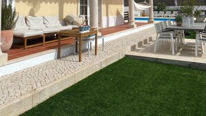 A covered outdoor seating area with a pool, white columns, and a tiled roof.