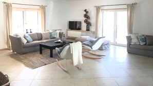 A modern living room with a sofa set, a coffee table, a TV, and a decorative plant.