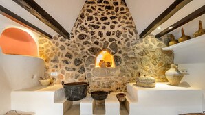 A stone fireplace with a small window, surrounded by white walls and wooden beams.