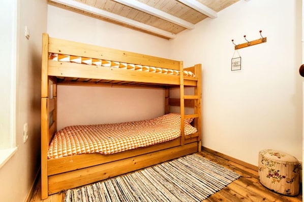A bunk bed with a checkered bedspread, a wooden floor, and a small rug. - Vacation home Martha (Veurne)