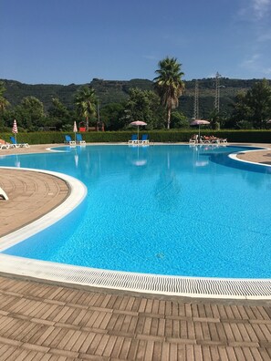 A clear blue swimming pool with lounge chairs and umbrellas, surrounded by greenery and hills. - Pizzo Beach Club “Summer Special” 2 Bed apartment 13F with  Free WIFI and 2 Terr (Pizzo)