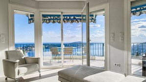 Un balcón con vista al mar, un sofá y una mesa de comedor con sillas.