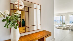 Una sala moderna con un espejo grande, una mesa consola de madera y vistas a la ciudad.