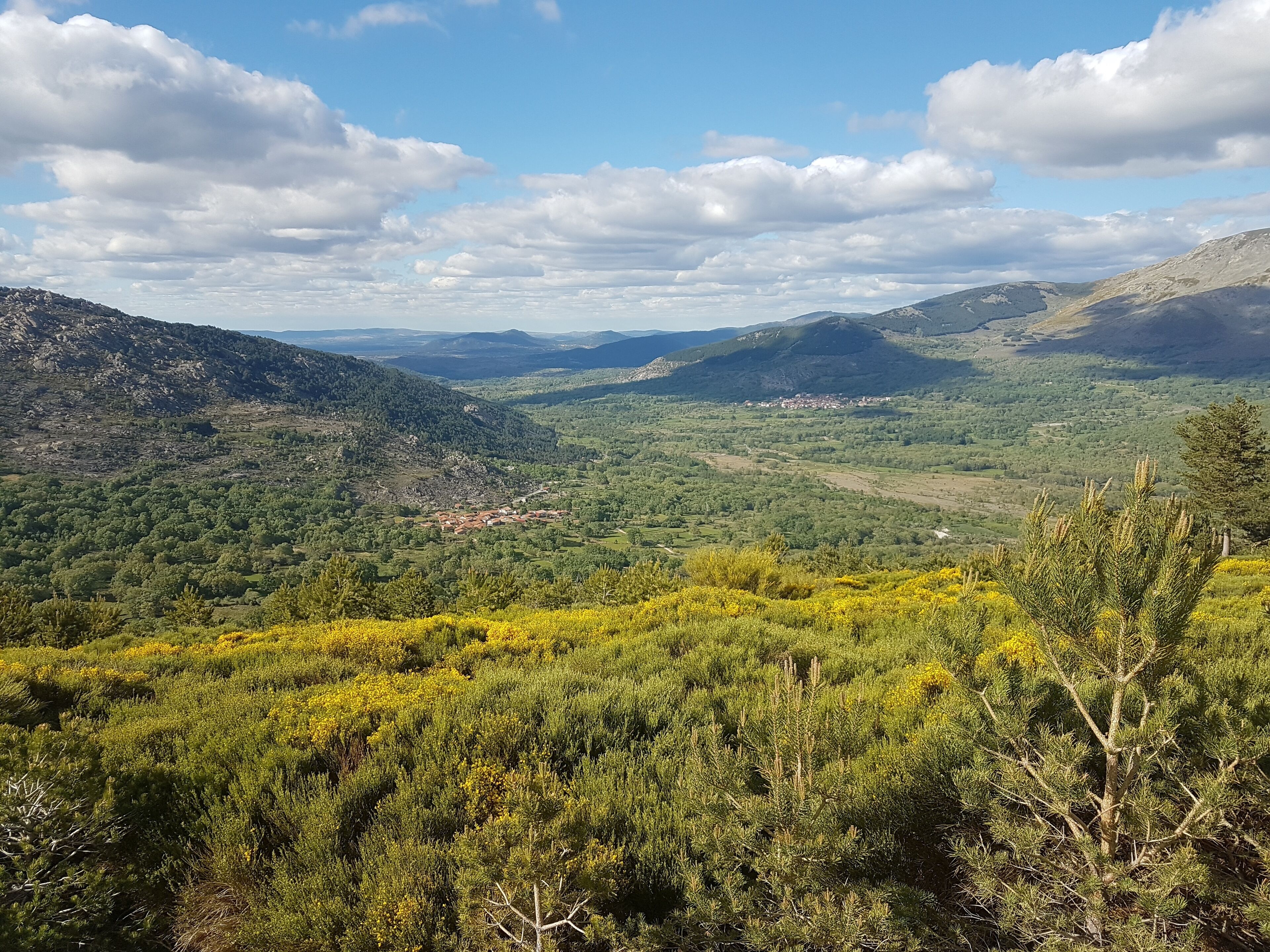 Un paysage montagneux comprenant une vallée, une végétation luxuriante et un petit village.