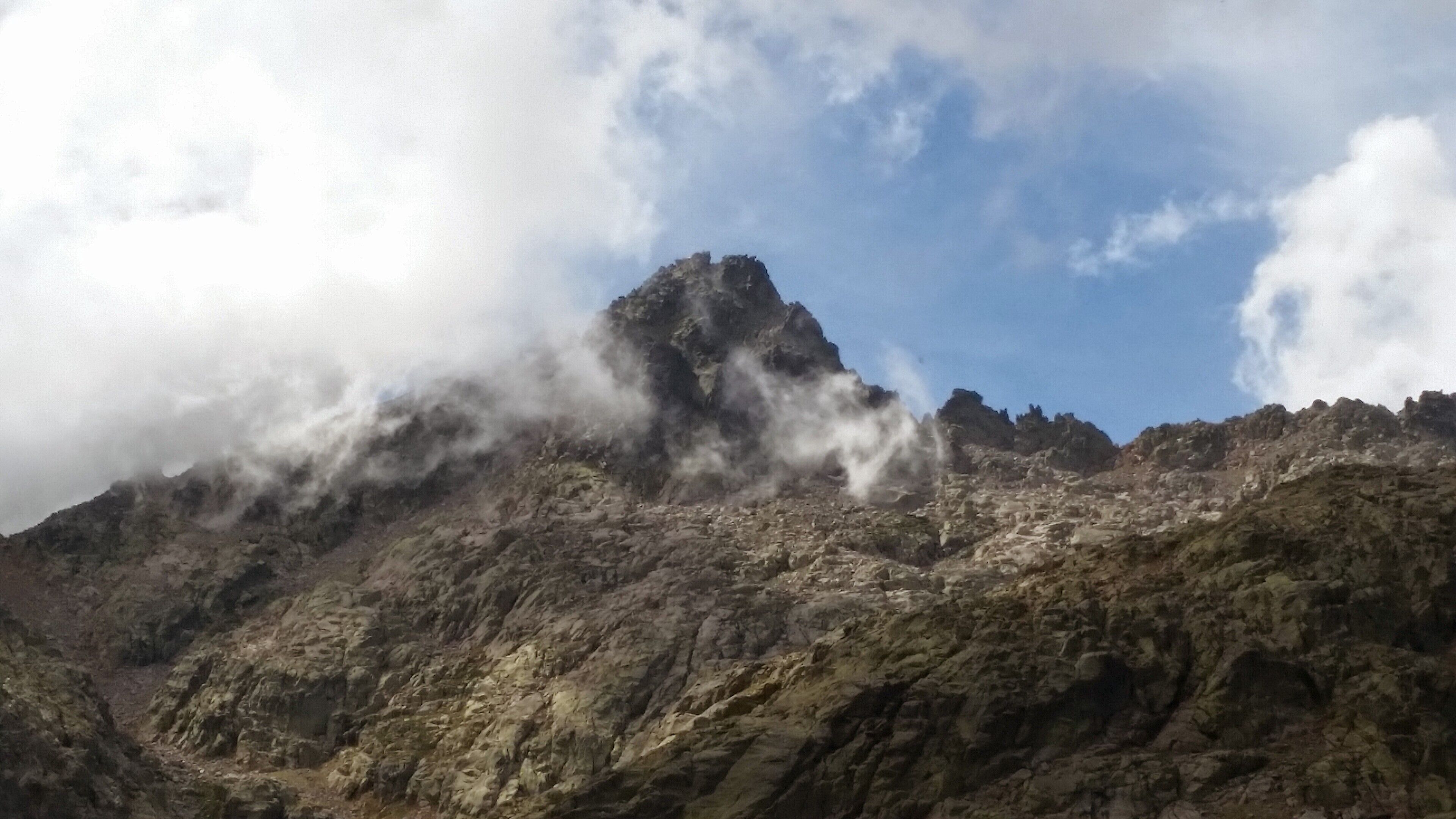 Un pico montañoso escarpado con nubes que lo cubren parcialmente.