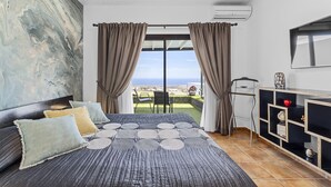 Un dormitorio con una cama grande, vistas al mar y un televisor en la pared.