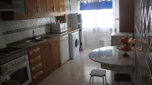 Una cocina con armarios de madera, microondas, lavadora y comedor con mesa y sillas.