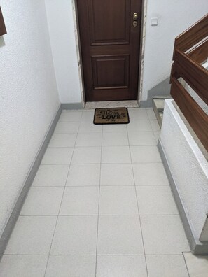 A hallway with a brown door, a doormat with 'Home Love' text, and a white wall.