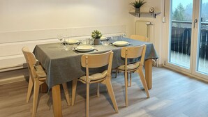 Zona pranzo con tavolo imbandito per quattro persone, sedie in legno e vista attraverso una porta vetrata.