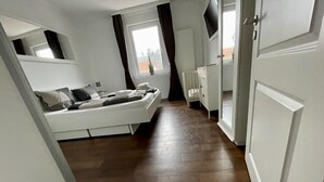 A narrow hallway leading to a bedroom with a bed, a radiator, and a window. - Luxury vacation rental centrally located and close to the beach. Wi-Fi free. (Norderney)