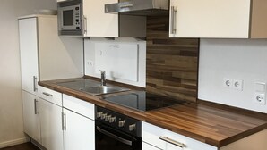 A modern kitchen with white cabinets, a stainless steel microwave, a built-in oven, and a wooden countertop. - Luxury vacation rental centrally located and close to the beach. Wi-Fi free. (Norderney)