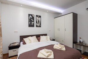 A bedroom with a bed, a nightstand, a wardrobe, and two framed pictures on the wall. - Luxury villa, Trogir - Ciovo, directly by the sea, heated pool, max. 12 pers.(+2 ) (Trogir)