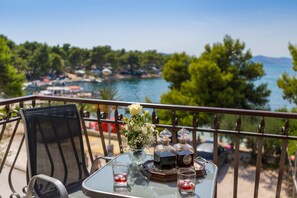 A balcony table with a glass top, two bottles, a glass, and a vase with flowers. - Luxury villa, Trogir - Ciovo, directly by the sea, heated pool, max. 12 pers.(+2 ) (Trogir)