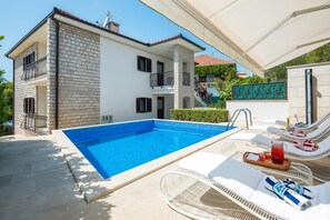 Un bâtiment à deux étages doté d’une piscine, d’un espace extérieur aménagé et d’une zone couverte.