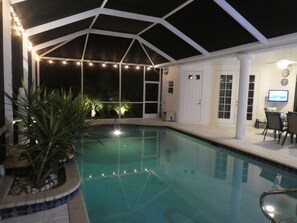 Area piscina con una zona coperta, una pianta in vaso e un televisore a parete.