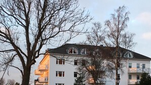 A multi-story building with balconies, a well-maintained garden, and a large rock feature in the foreground. - Feel-good apartment StrandGut für Ostseegenießer, Hs. Atlantic (Grömitz)