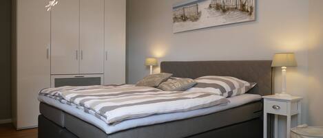 A bedroom with a bed, bedside tables, a wardrobe, and a painting on the wall.