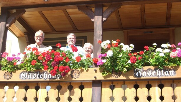A wooden balcony with flower boxes labeled "Gästhaus" and "Wazchian".