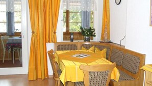 A dining area with a table and benches, yellow tablecloths, and a clock on the wall.