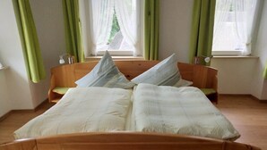 A bed with a wooden headboard, two pillows, and a green curtain.