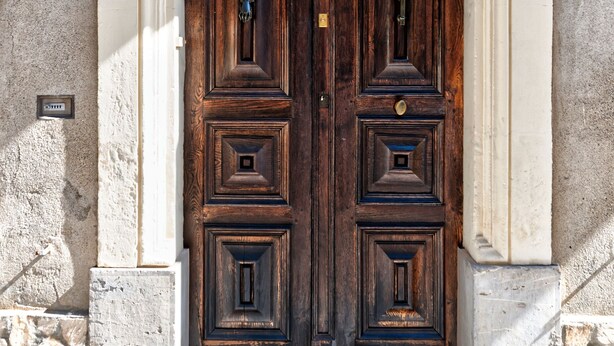 Una puerta doble de madera con una placa numérica encima.